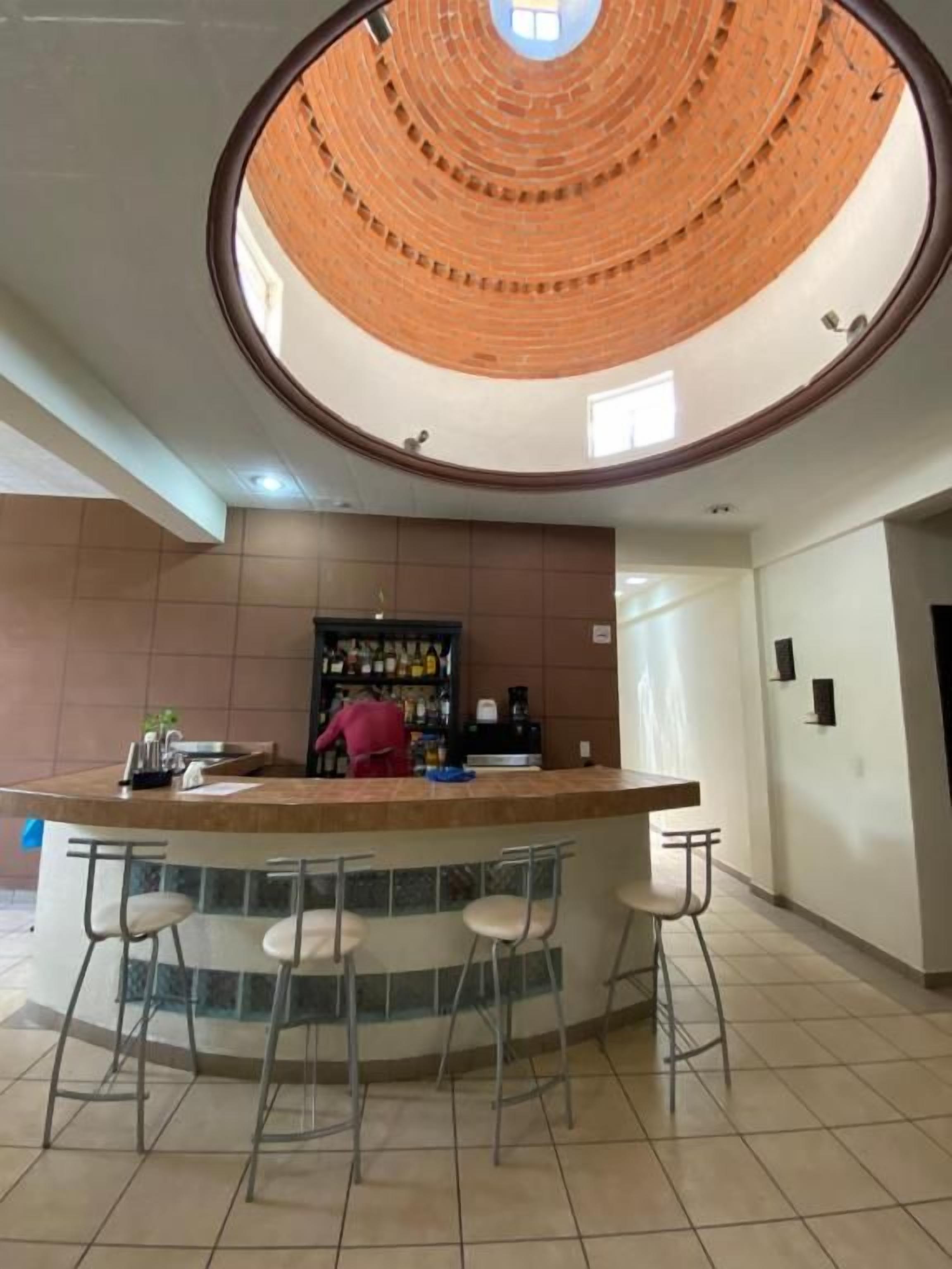 Un bar circular con taburetes, una barra y suelo de baldosas.