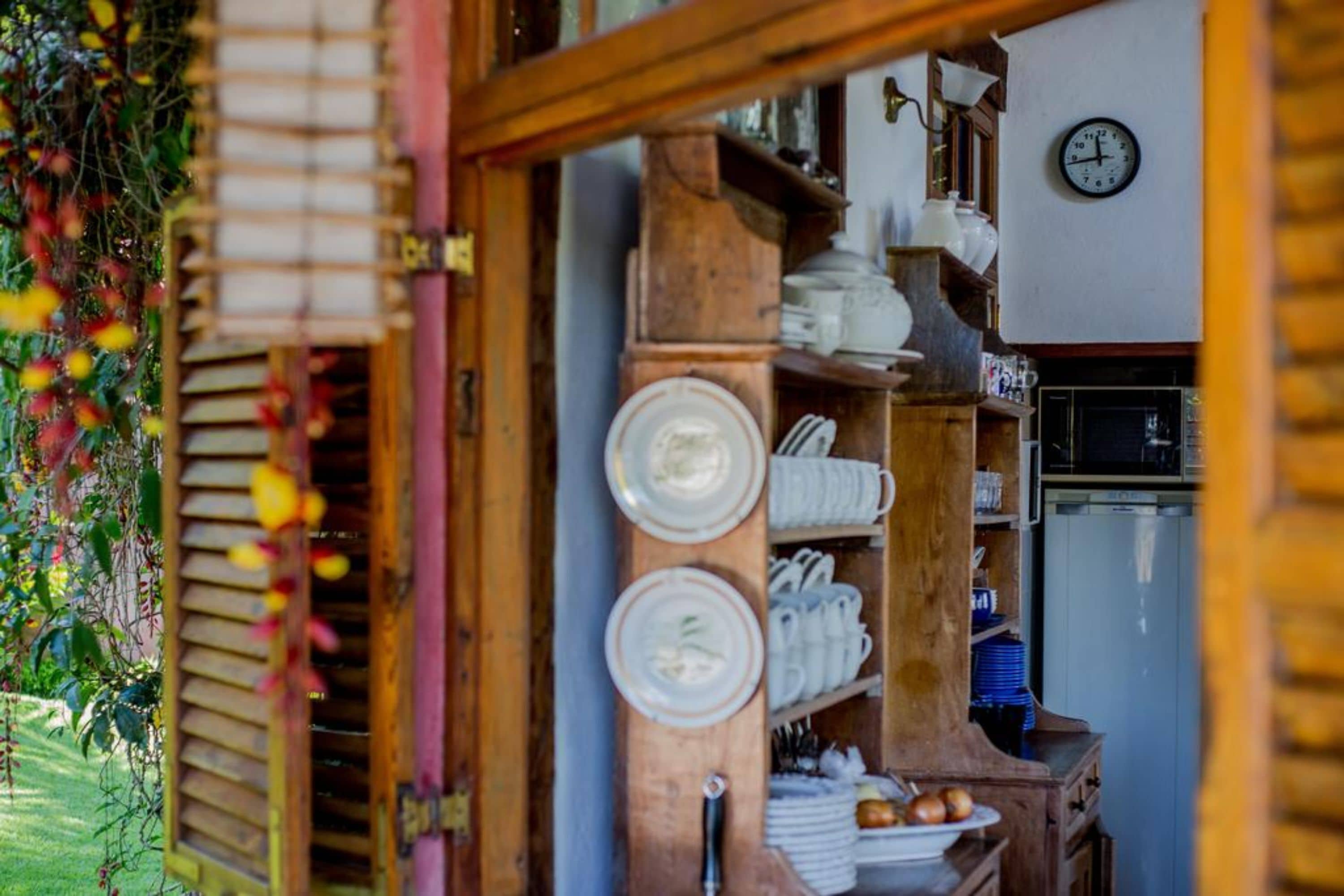 Une cuisine rustique avec des étagères en bois, une horloge et un réfrigérateur.