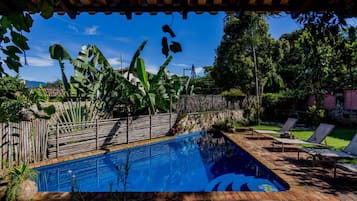 Una piscina al aire libre, sillones reclinables de piscina