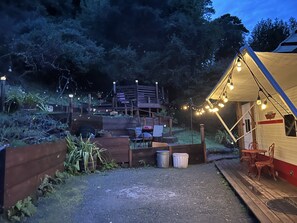 A campsite with a wooden deck, a covered seating area, and string lights. - Meet the Ruby! (Inverness)
