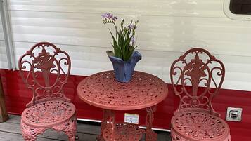 A red metal table and chairs set against a white RV with a 'Retro Riverside RV' logo.