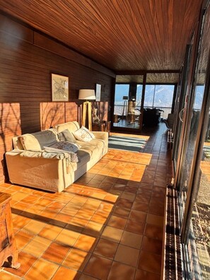 A cozy room with a sofa, a lamp, and a large window.