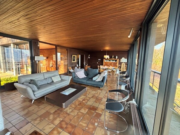 A modern living room with two sofas, a coffee table, and a dining area with chairs and a table.