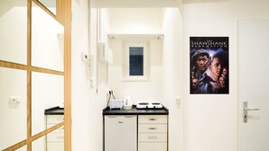 Een compacte keuken met een koelkast, een klein raam en een poster van 'The Shawshank Redemption' aan de muur.