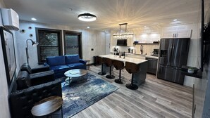 Una cocina moderna con una isla central, taburetes de bar y un refrigerador empotrado.