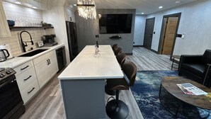 Una cocina moderna con una isla central, una zona de comedor con una mesa redonda y un espacio de estar con sofá.