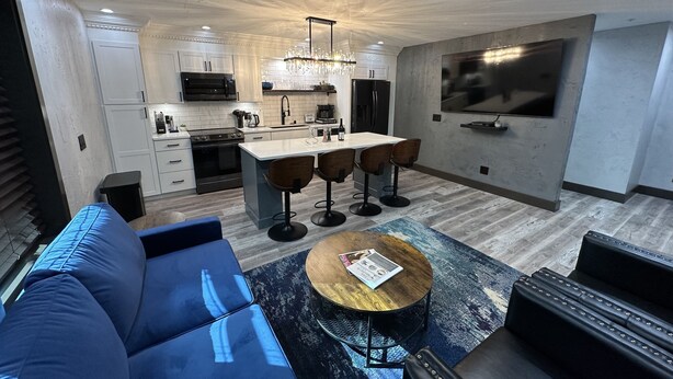 Una cocina moderna con una isla central, taburetes de bar y una mesa de comedor.