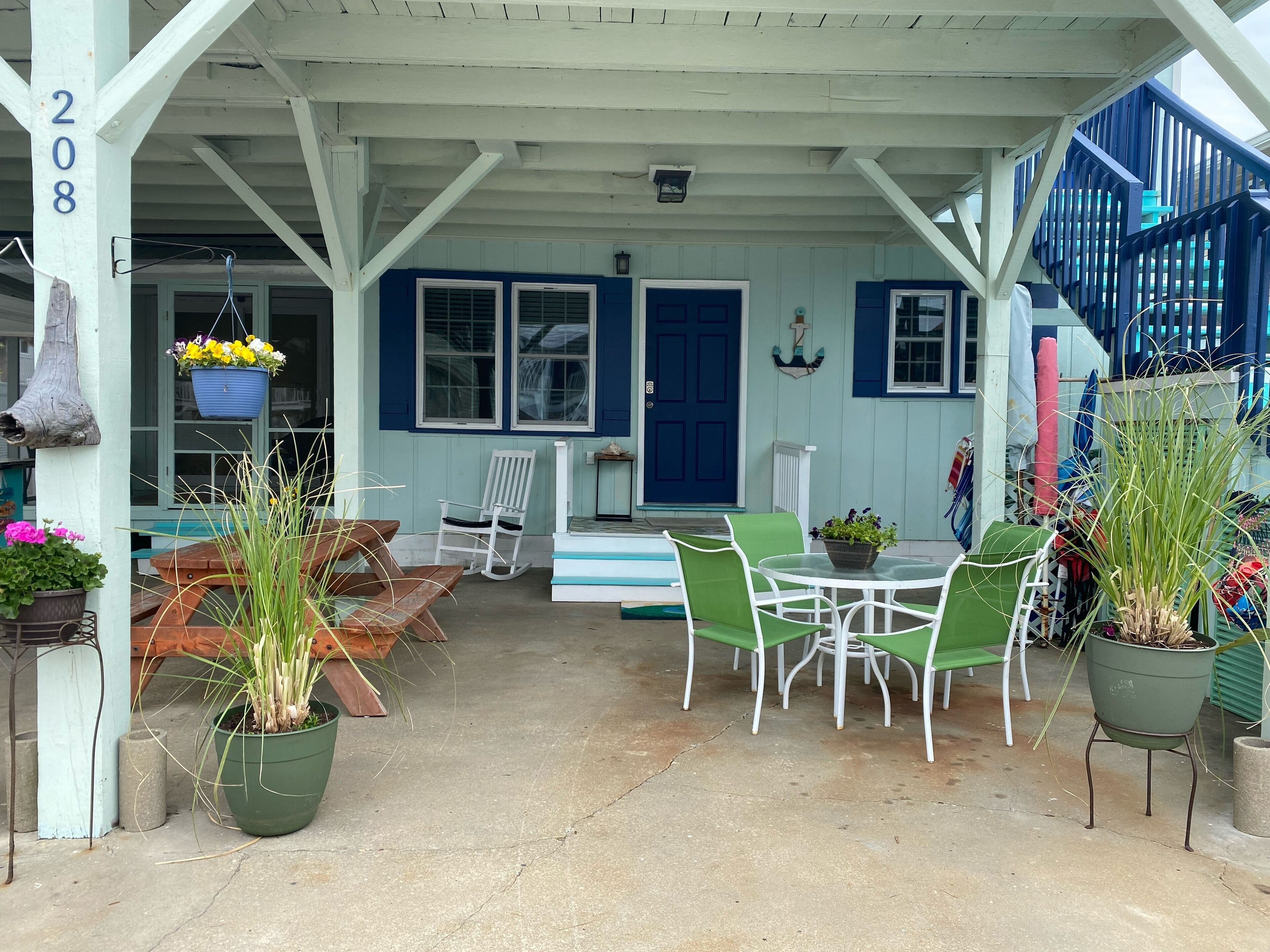 A covered porch with outdoor seating, a blue door, and a staircase.