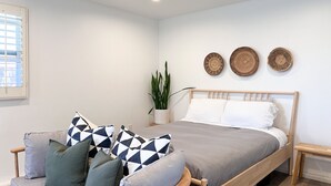 Une chambre avec un lit en bois, un canapé gris et une plante en pot.