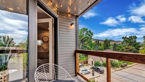 Un balcon avec une chaise blanche, une petite table et un pot de fleurs.