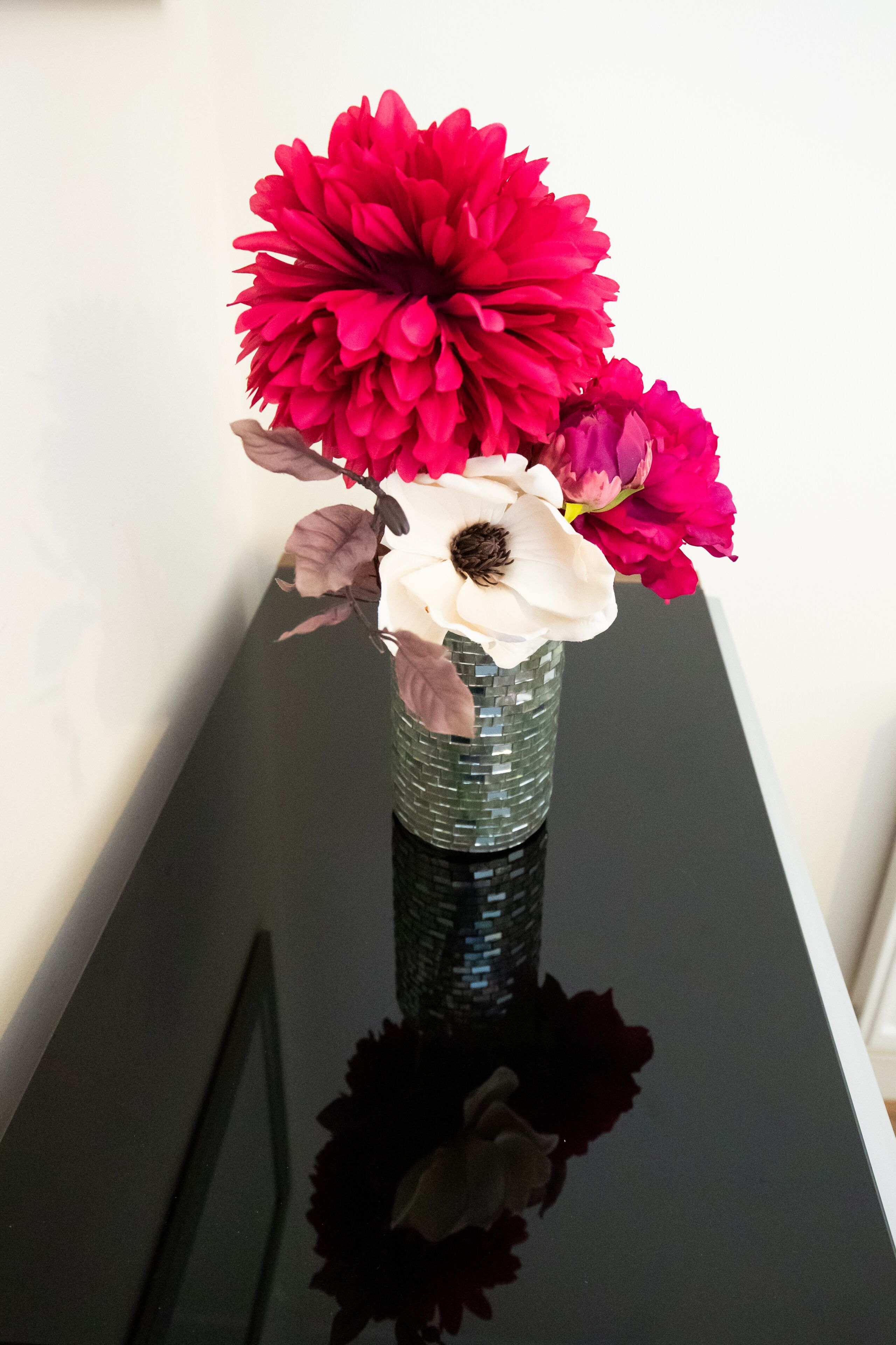 A vase with flowers on a reflective surface.
