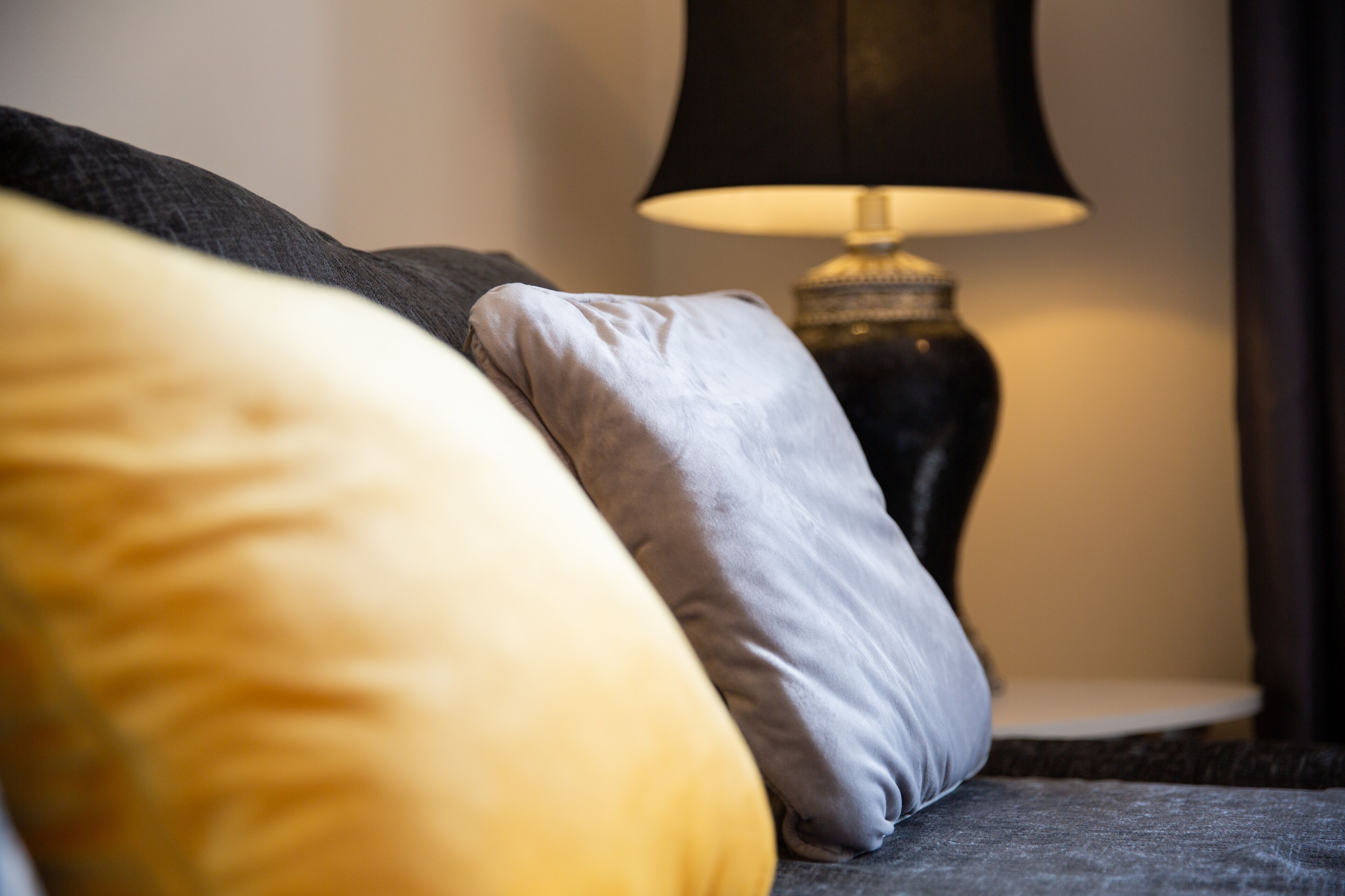 A close-up of a bed with pillows and a lamp in the background.