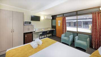 Une chambre d’hôtel équipée d’un lit, d’un bureau, d’un four à micro-ondes, d’une télévision et de deux chaises.