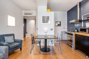 A modern kitchen with a dining area, a grey sofa, and a framed picture on the wall. - Piazza Santa Croce Design Apartment con Balcone (Firenze)