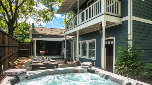 Ein Garten mit Whirlpool, einem Essplatz komplett mit Geschirr und Gläsern, und einer überdachten Terrasse.