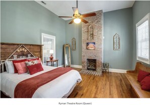 Une chambre avec un grand lit, une cheminée, un ventilateur de plafond et un banc.