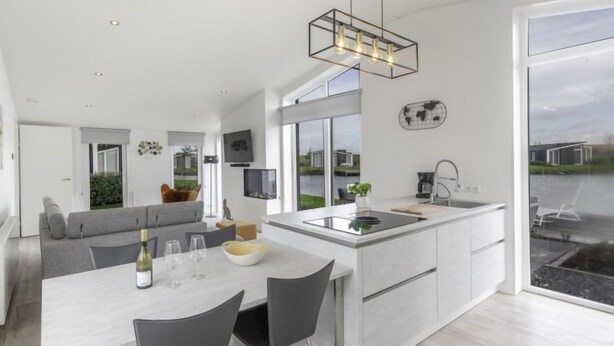 Une cuisine moderne dotée d’un îlot central, d’un coin repas avec des chaises et d’une grande fenêtre donnant sur l’extérieur.