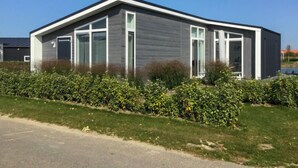 Une maison moderne de plain-pied, avec une façade grise, de grandes fenêtres et un jardin bien entretenu.