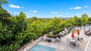 A rooftop patio with outdoor seating, a barbecue area, and a view of the surrounding greenery.