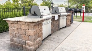 A stone-built outdoor grill station with two built-in grills and a stone countertop.
