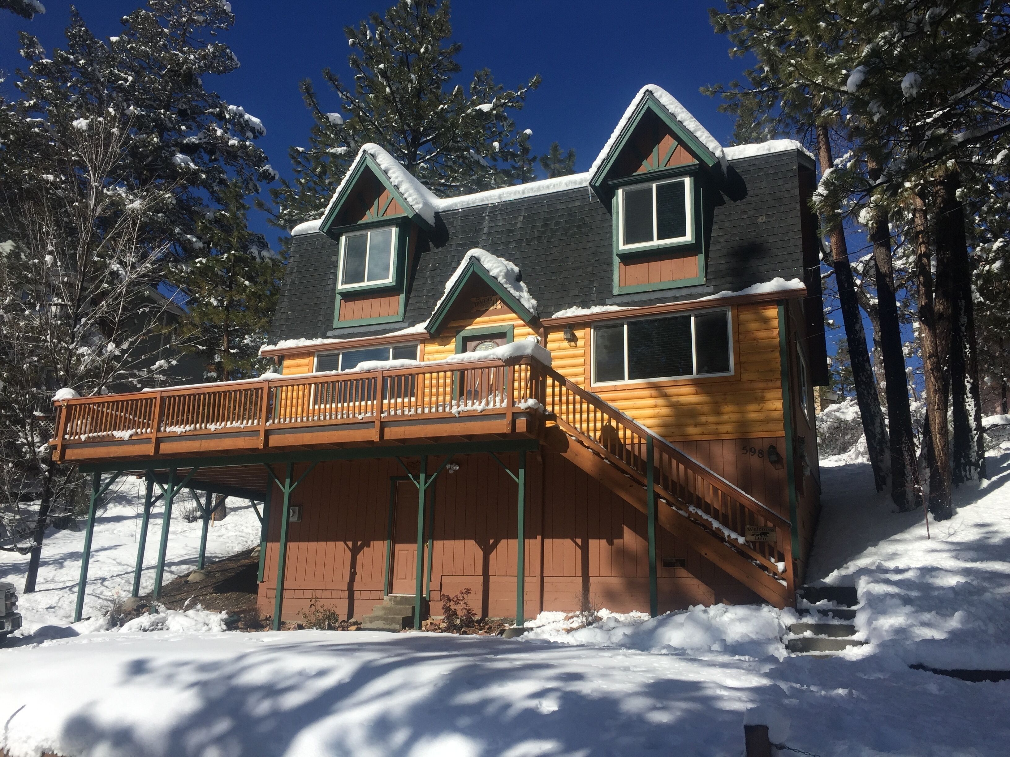 A wooden cabin with a balcony, surrounded by snow-covered trees.
