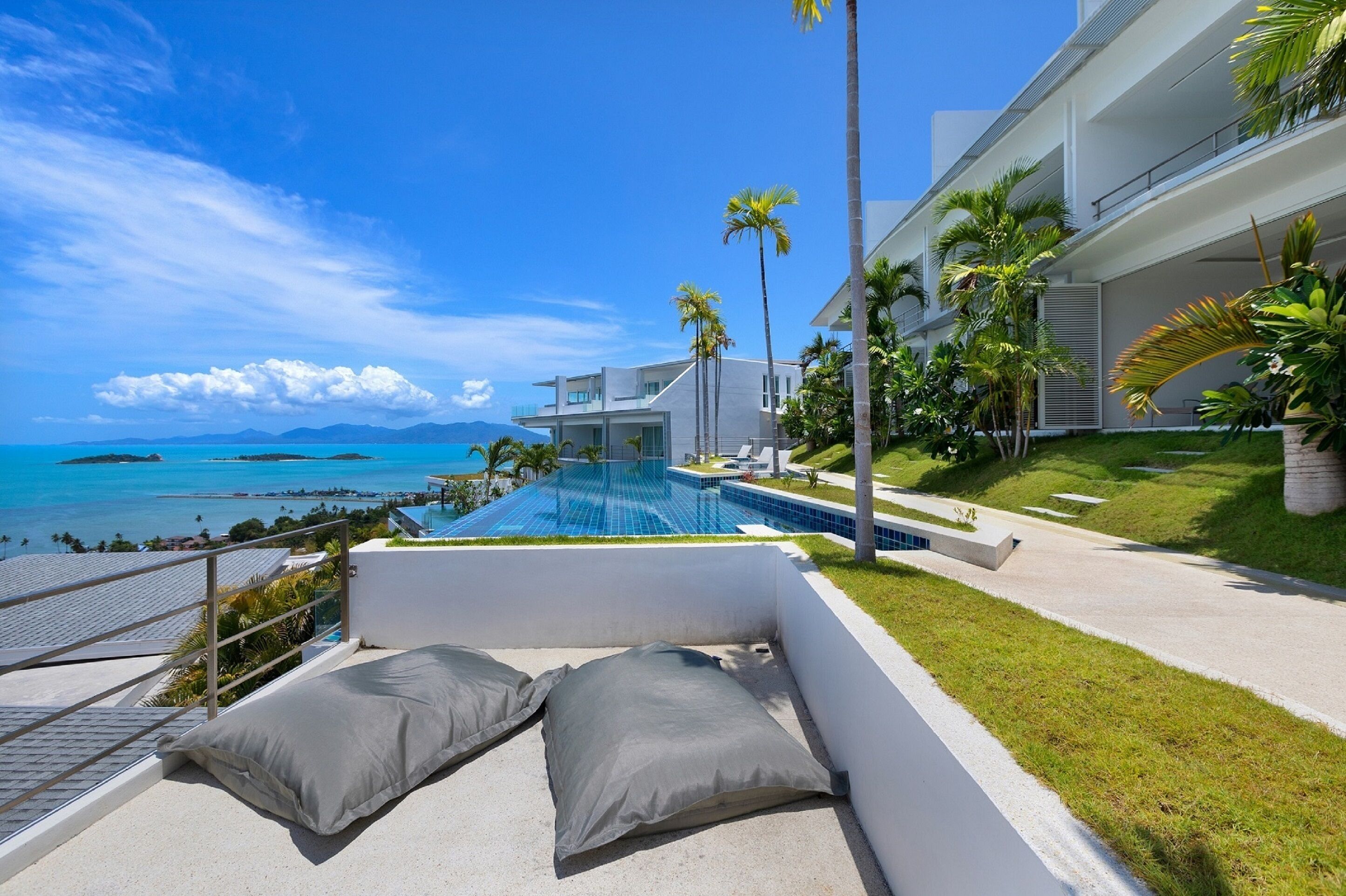 Un hotel moderno con piscina, palmeras y vista al océano.