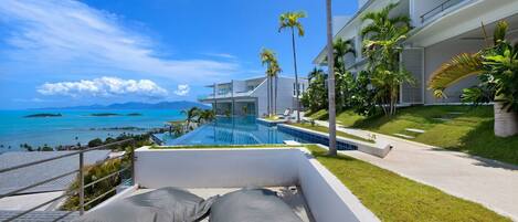 Un hotel moderno con piscina, palmeras y vista al océano.