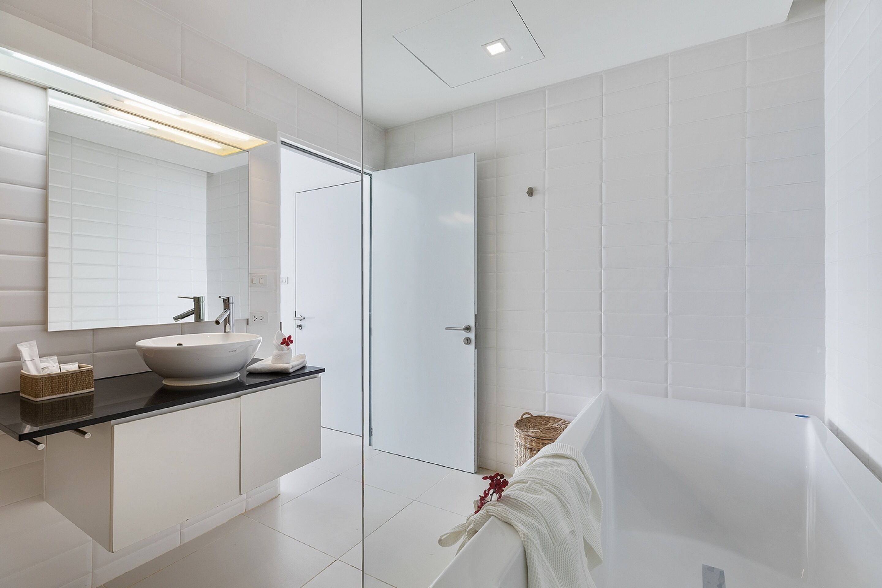 A modern bathroom with a white sink, mirror, and bathtub.