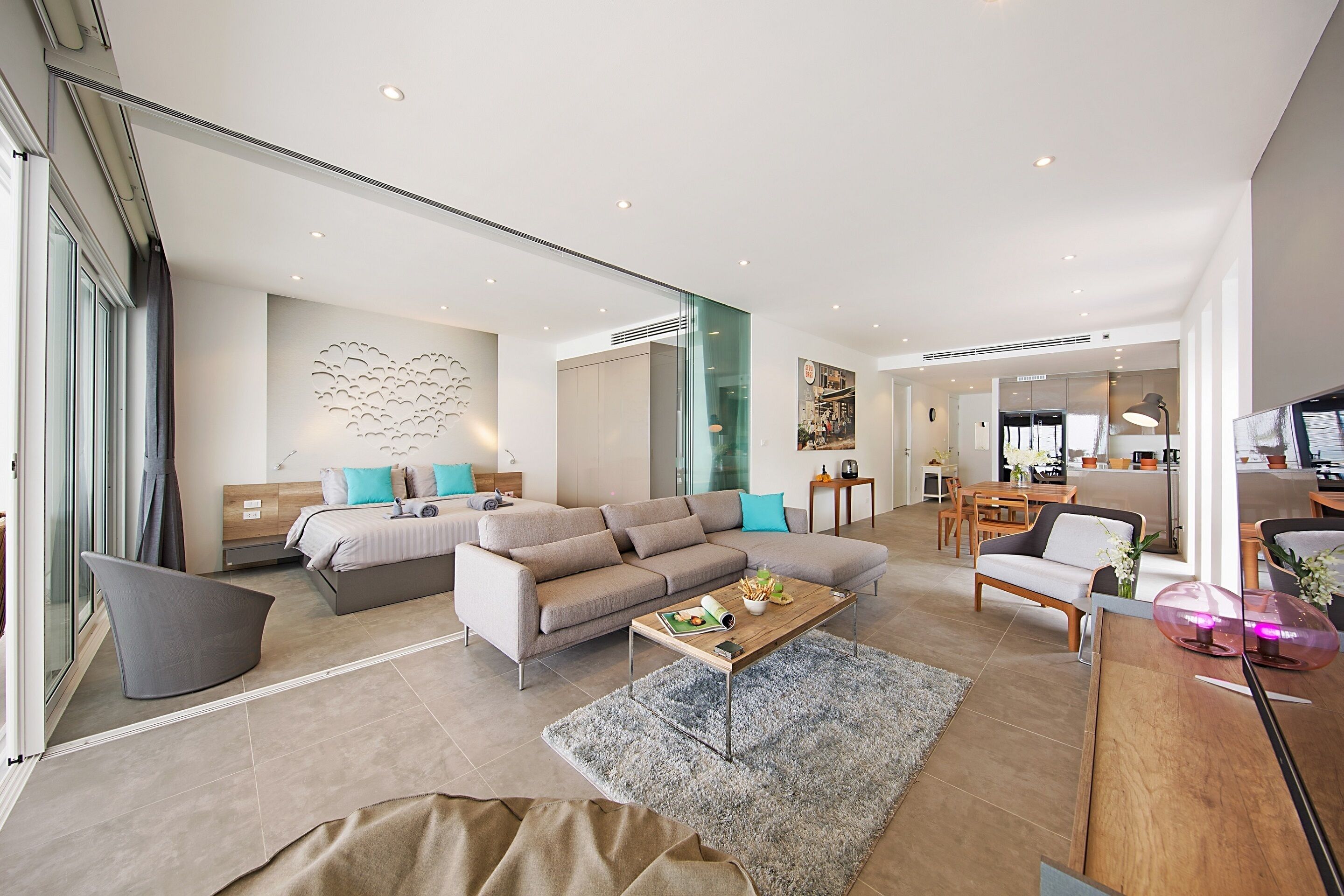 A modern living room with a sofa, coffee table, and a dining area.