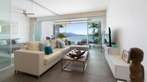A modern living room with a large sofa, a coffee table, and a view of the sea. - Luxury Apartment Unique Residences (Koh Samui)