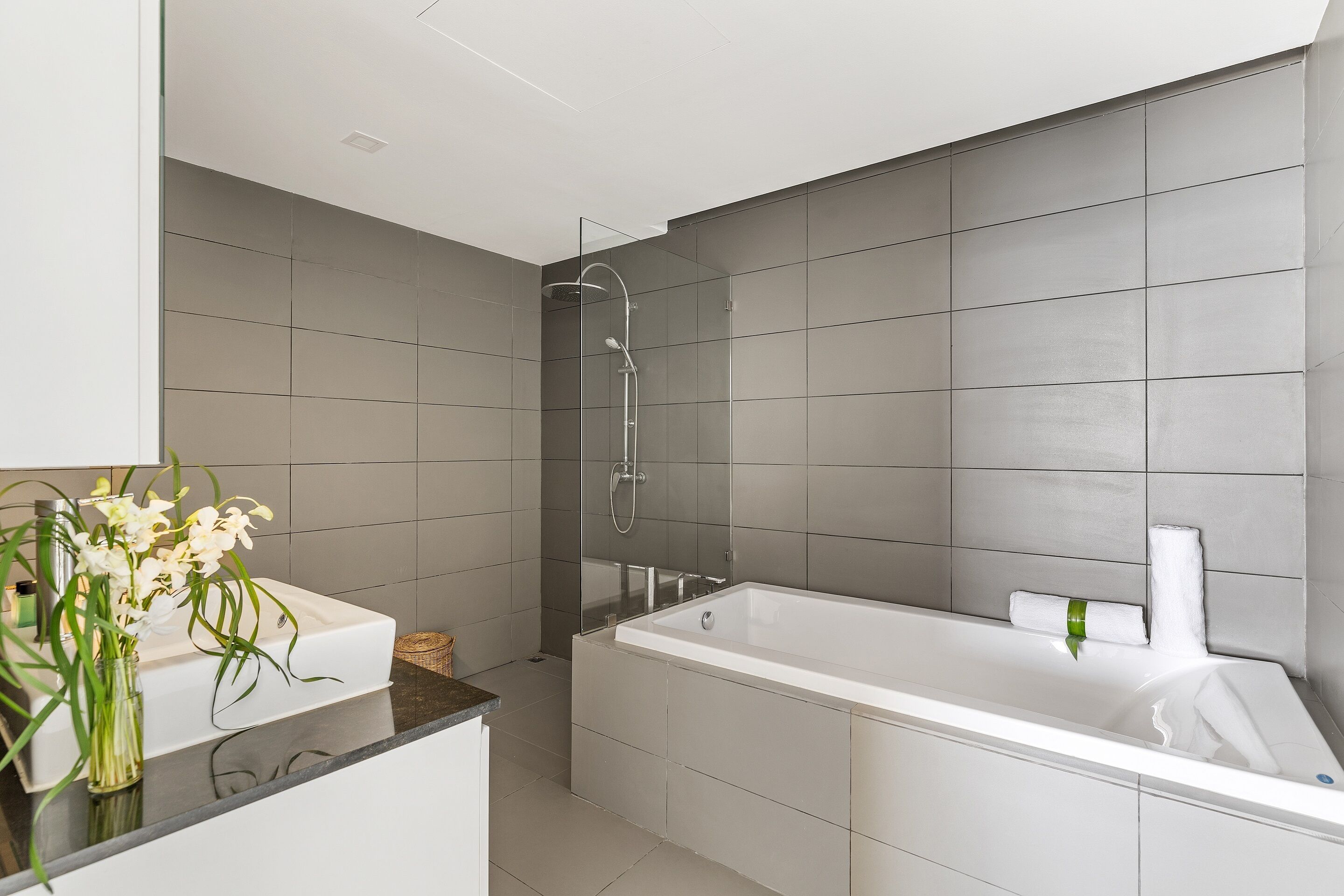 A modern bathroom with a large bathtub, a shower, and a sink.