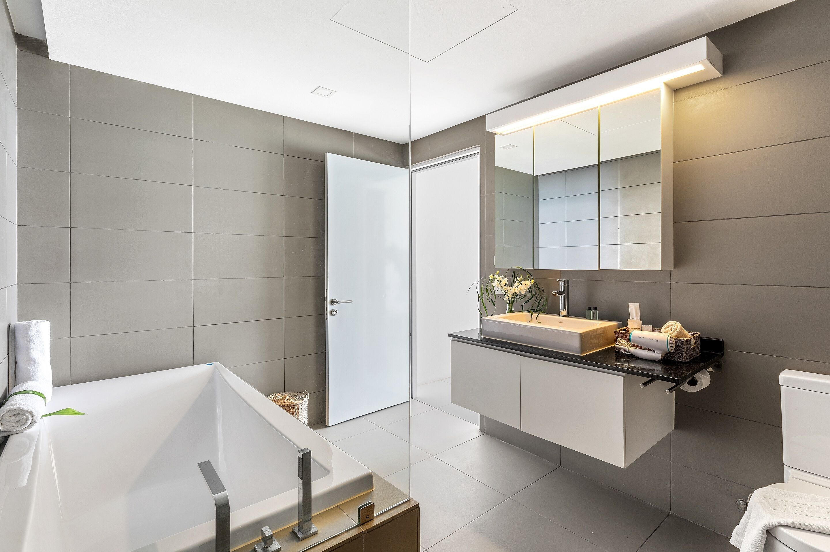 A modern bathroom with a large bathtub, a vanity with a mirror, and a toilet.