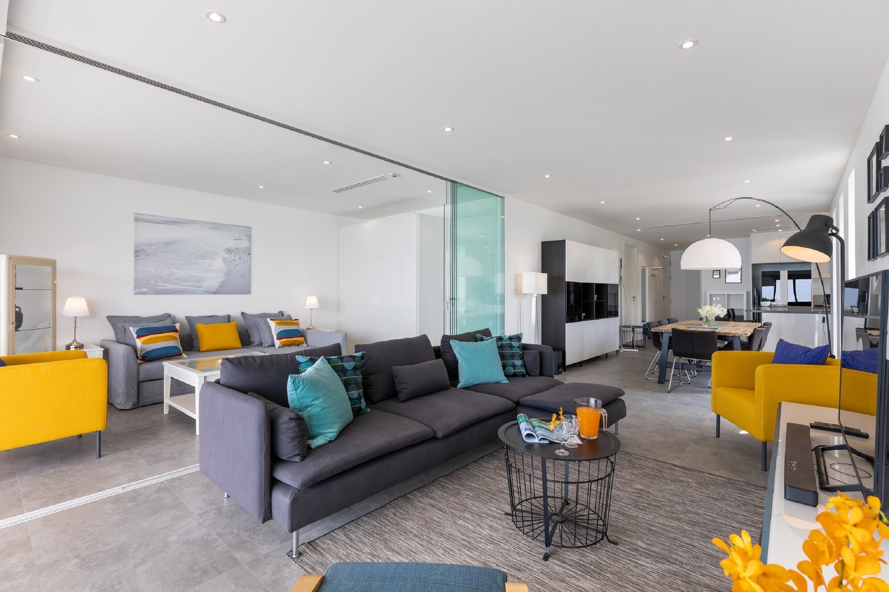 A modern living room with a sectional sofa, a coffee table, and a dining area with a table and chairs.