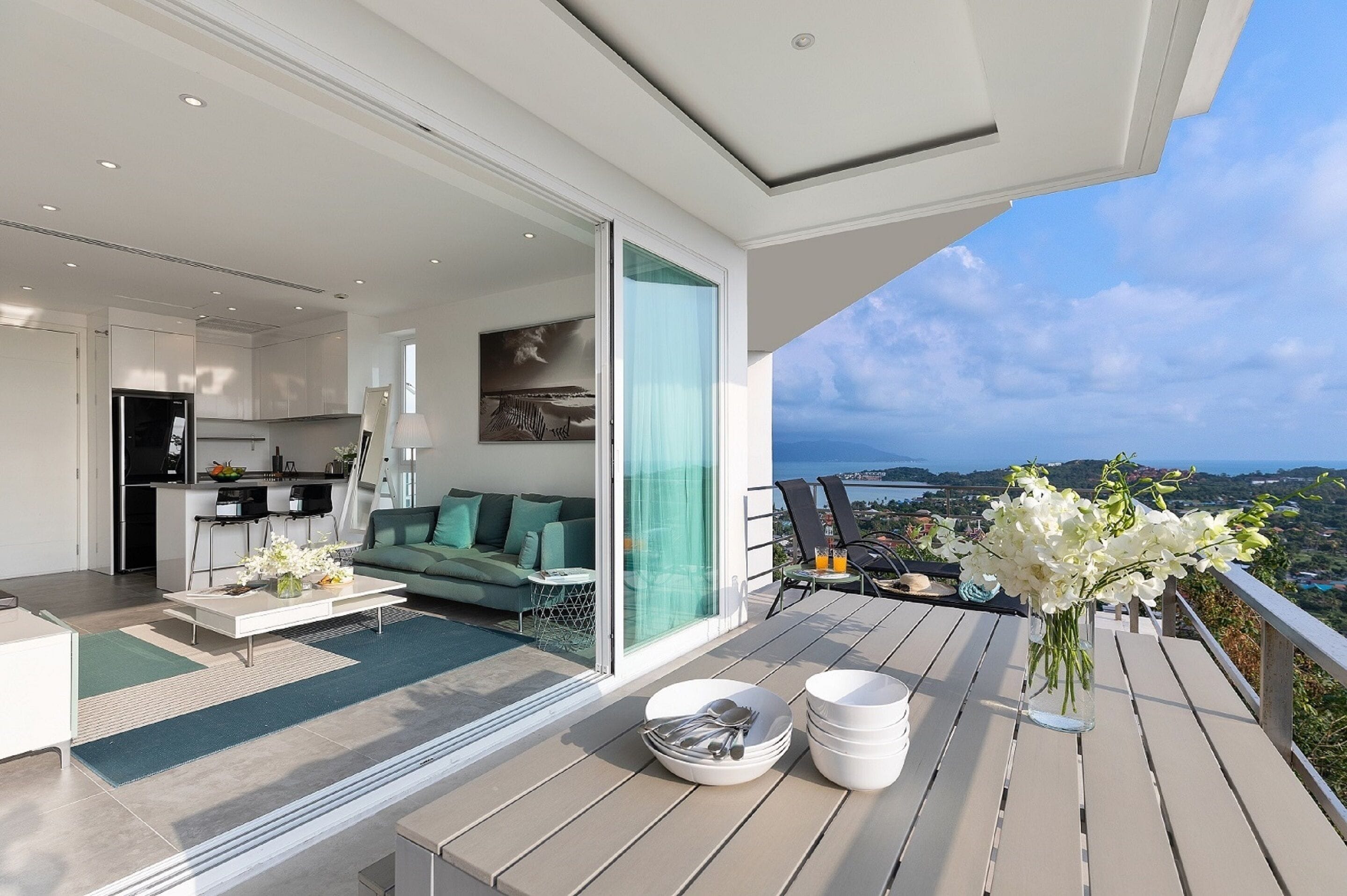 A modern living space with a balcony, a dining area, and a kitchen.