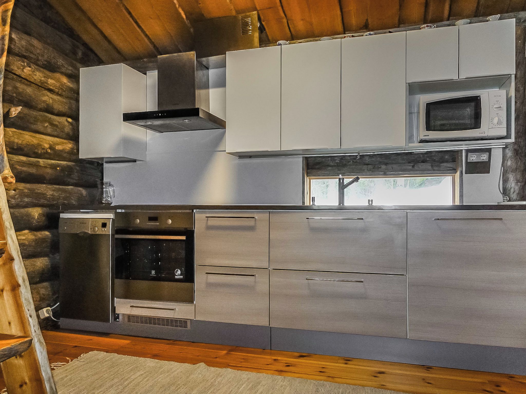 Cozinha moderna com eletrodomésticos de aço inoxidável, incluindo micro-ondas, forno e lava-louças.