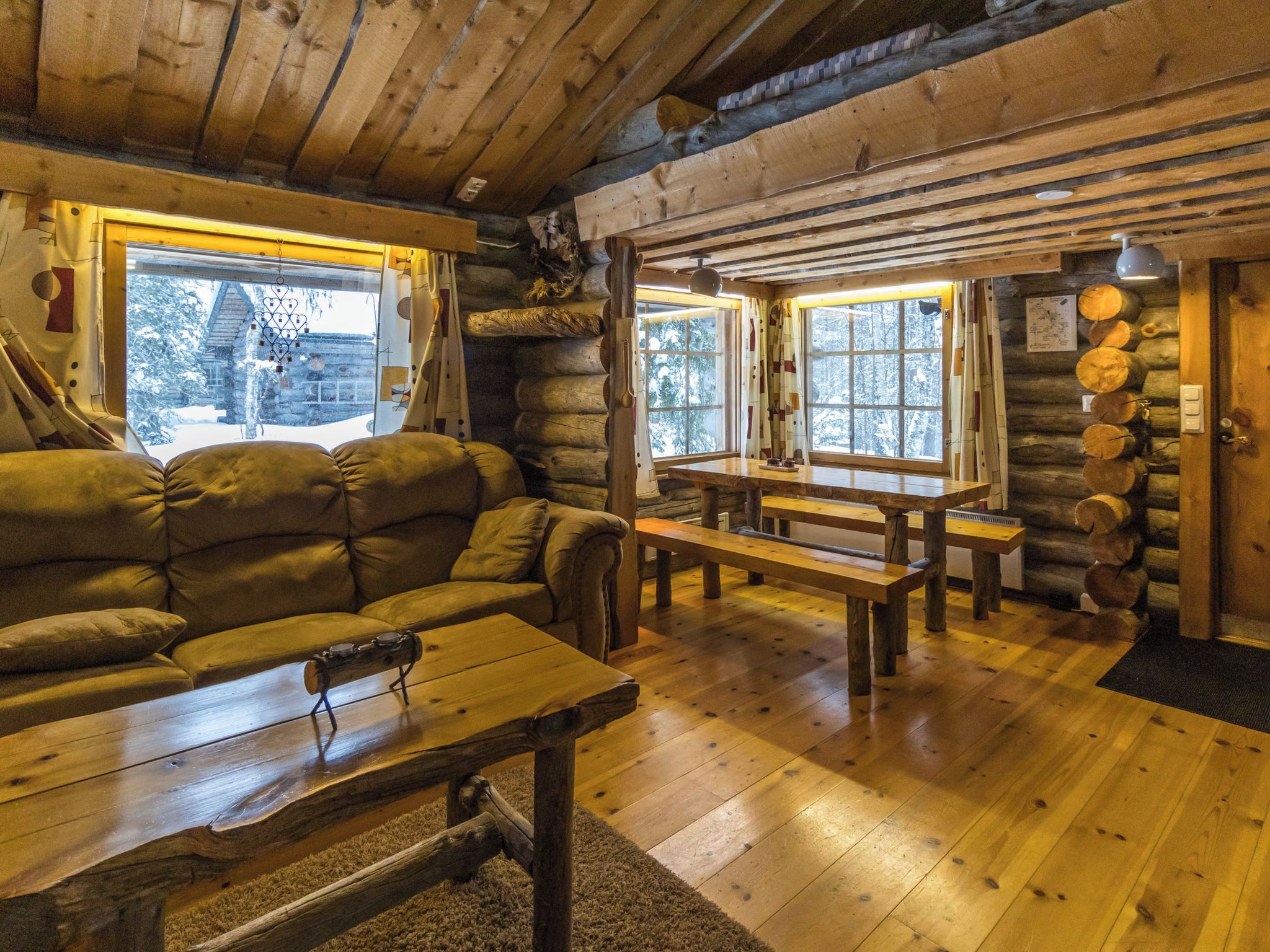A log cabin interior with a sofa, wooden benches, and a table.