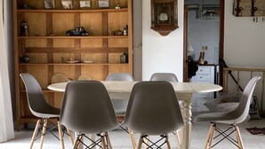 Un'area pranzo con un tavolo rotondo e sei sedie, una libreria in legno e un orologio appeso al muro.