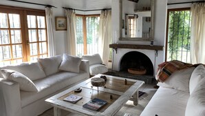 Un ampio soggiorno con camino, divani bianchi e un tavolino da caffè con libri.