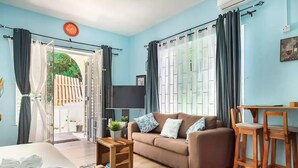 A room with a bed, a sofa, a wooden table, a TV, and a window with curtains. - clean, comfy & quiet with views  (Tower Isle)