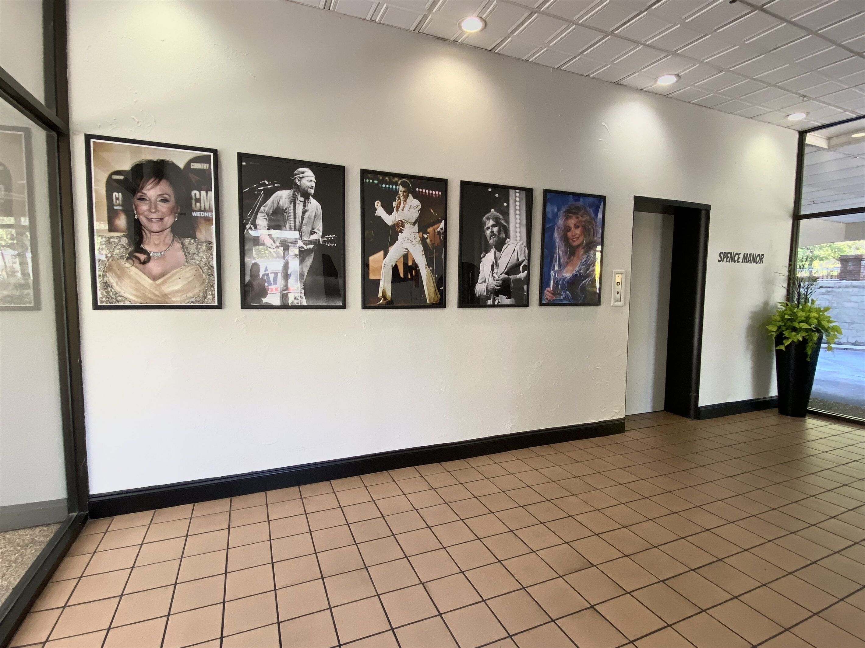 A hallway with a tiled floor and a series of framed pictures on the wall.