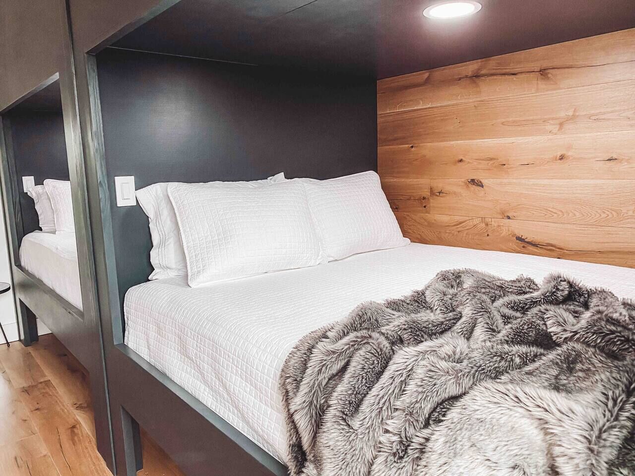 Uma cama beliche com colcha acolchoada branca e um cobertor cinza fofo.