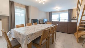 Un espace repas comprenant une table et des chaises, un canapé, un téléviseur et un escalier.