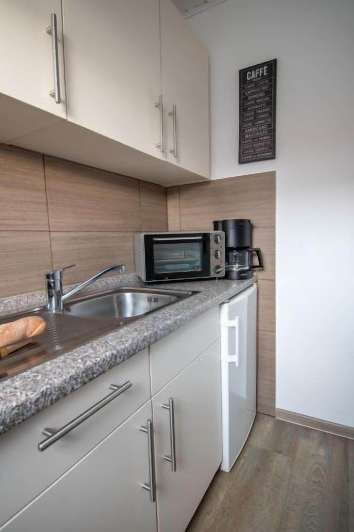 A modern kitchen with a built-in microwave, coffee maker, and stainless steel sink.