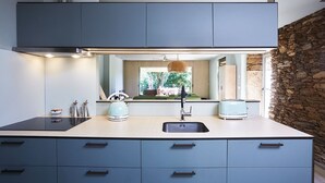 A modern kitchen with a central island, a built-in stove, and a stone accent wall.