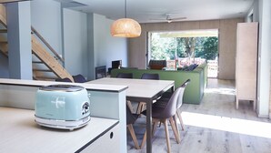 A modern kitchen with a light blue toaster, wooden chairs, a dining table, and a hanging light fixture.