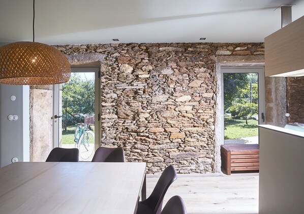 Un comedor moderno con pared de piedra, una mesa de madera y sillas.