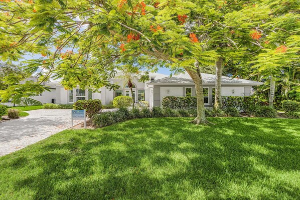 A residential property with a well-maintained lawn, a driveway, and a sign indicating the property is for sale.