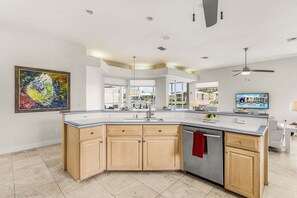 Una cocina moderna con una isla grande, un comedor y vistas al exterior.