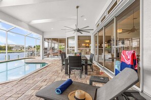 Un espacio al aire libre techado con piscina, mobiliario y vista al agua.