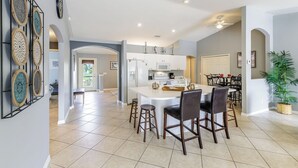 A spacious kitchen with a central island, modern appliances, and a dining area with bar stools. - Southern Exposure home, Large lanai, Pool and Spa - Villa Palms - Roelens Vacations (Cape Coral)